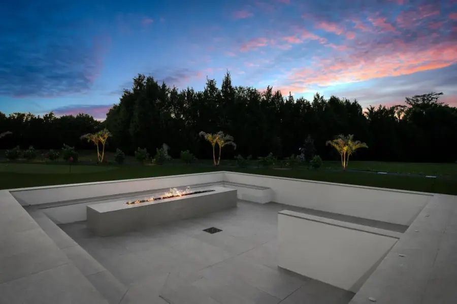 A cozy backyard fire pit glowing warmly under the twilight, surrounded by comfortable seating and modern landscaping.