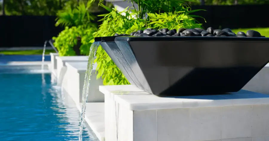 Black fire and water bowl spilling into a modern pool