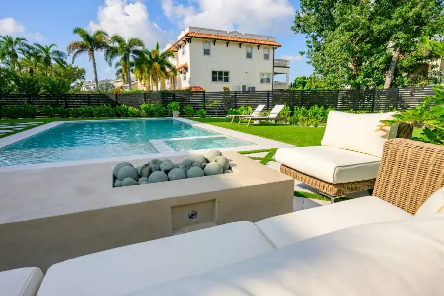 Outdoor seating area with a cozy cushioned setup, overlooking the pool and greenery.