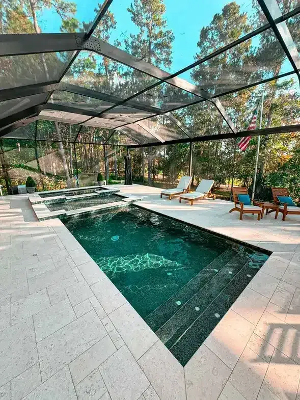 Screen-enclosed custom pool and raised spa with lounge chairs and an American flag