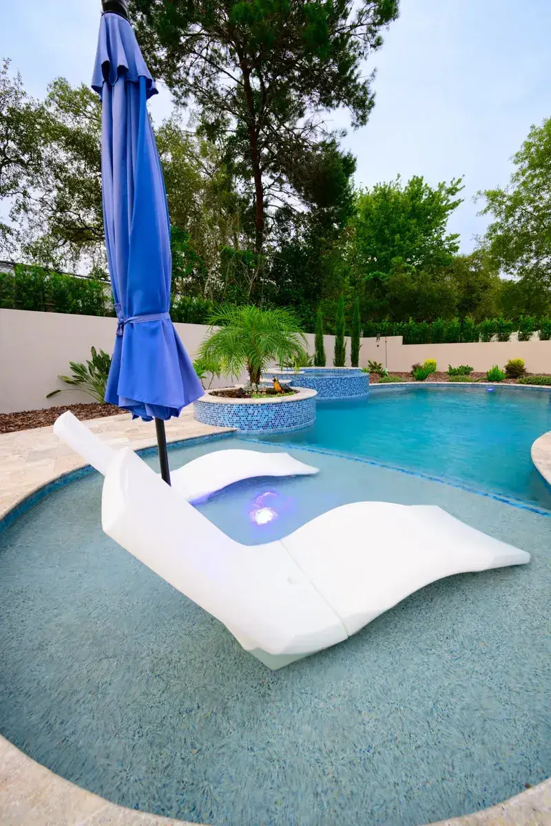 Lounge chairs on the sun shelf of a backyard pool