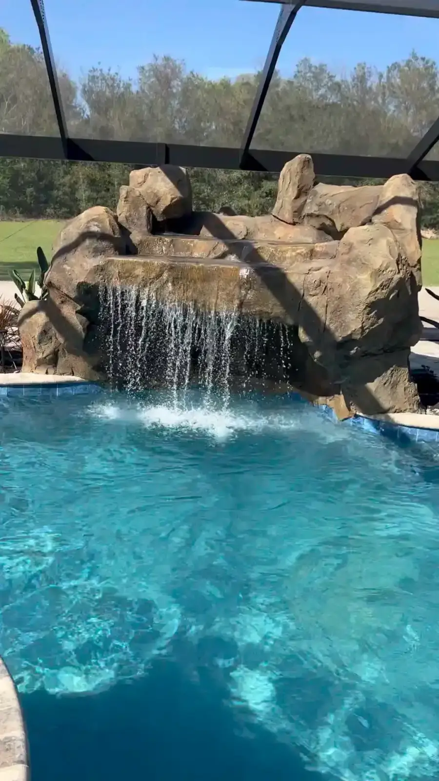 Custom rock waterfall spilling into a screened pool