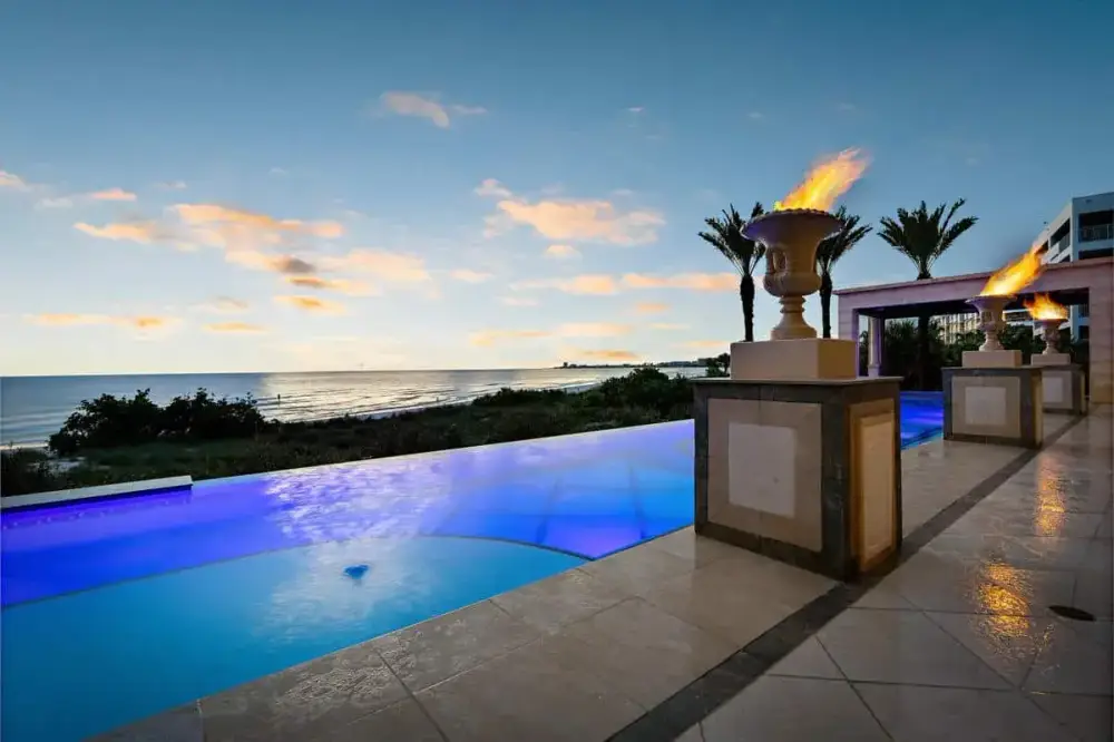 Custom Tampa pool featuring fire bowls and vibrant lighting, designed for a dramatic evening setting.