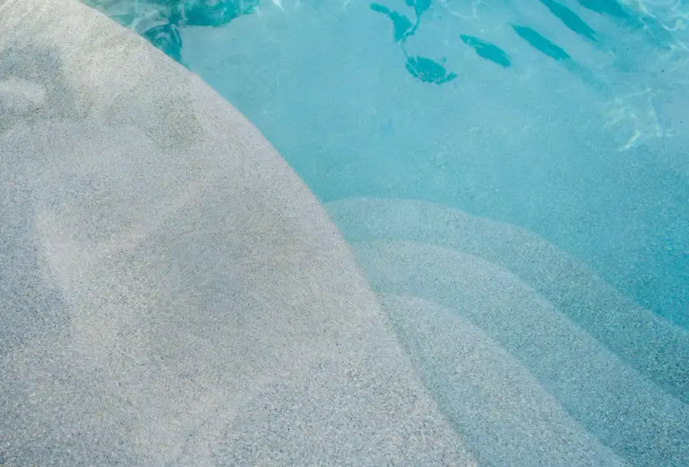 Close-up of shallow entry steps with textured surface, showing the smooth transition from pool deck into water.